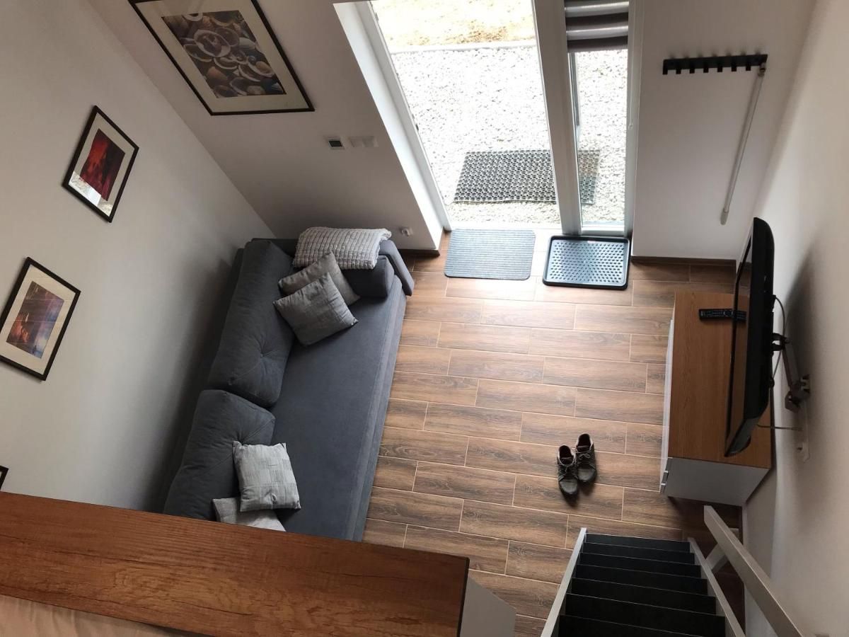 Salon widziany z góry: szara sofa, telewizor i przeszklone drzwi
