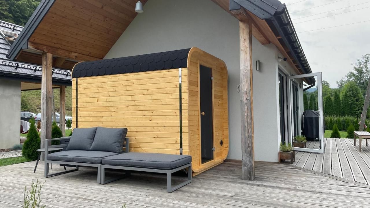 Szara sofa ogrodowa na tarasie przy białym domku